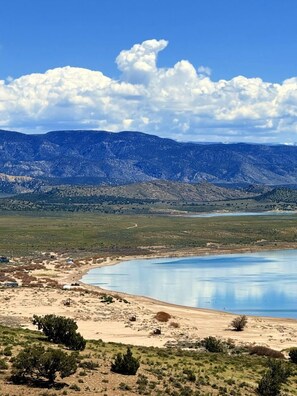 Un lago rodeado de montañas, cielo despejado y vegetación escasa.