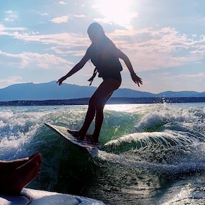 A person surfing on a wave with mountains in the background.