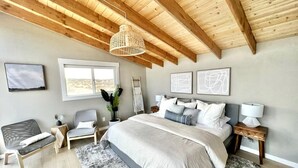 Une chambre avec un grand lit, un plafond en bois, une fenêtre et une table de chevet.