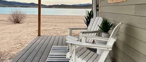 Un muelle de madera con sillas Adirondack y vistas a un lago.