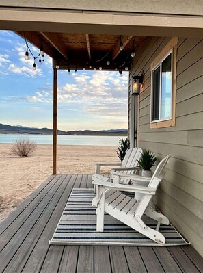 Un muelle de madera con sillas Adirondack y vistas a un lago.