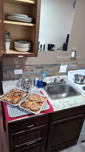 Una cocina con encimera de granito, pileta de acero inoxidable y escurreplatos.