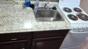 A kitchen with a granite countertop, stainless steel sink, and a white gas stove.
