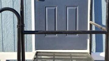 A metal step ladder in front of a blue door with a white 'B' on it.