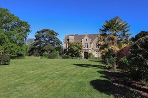 A large, historic building with a well-maintained lawn and mature trees. - The Old Stables (Gloucester)
