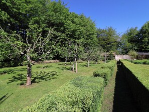 A landscaped garden with trees, a hedge, and a brick wall. - The Old Stables (Gloucester)