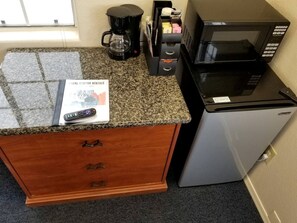 Eine Küche mit Granitabdeckung, einer Kaffeemaschine, einer Mikrowelle und einem Kühlschrank.