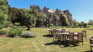 A large stone building with multiple windows and a lawn with wooden tables and chairs. - Harness Rooms (Gloucester)