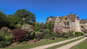 A large stone building with multiple windows and a garden with various plants and a pathway. - Harness Rooms (Gloucester)