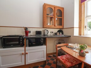 Eine kleine Küche mit zwei eingebauten Backöfen, einem Toaster, einem Wasserkocher und einem Holzkorpus über der Arbeitsplatte.