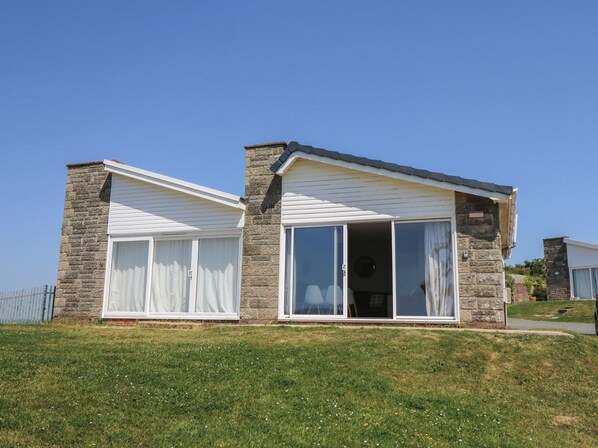 Ein modernes Haus mit Naturstein-Fassade, großen Schiebegläsern und einem geneigten Dach.