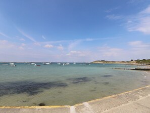 Eine Küstenlandschaft mit Booten, klarem Wasser und einem Sandstrand.