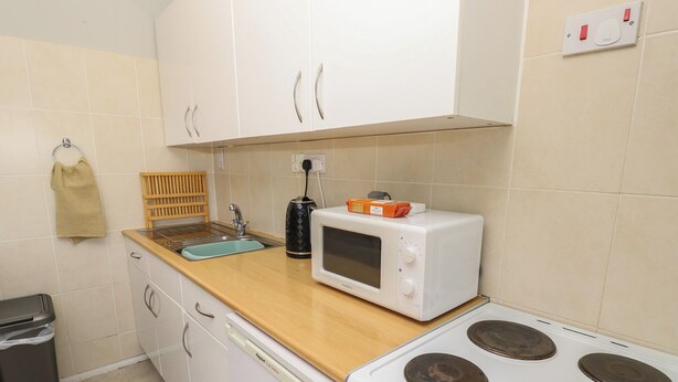Una cocina compacta con pileta, microondas y estufa.