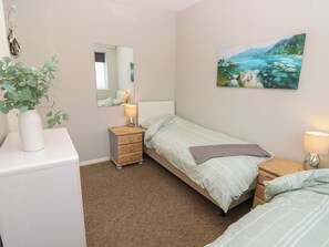 Ein Schlafzimmer mit einem Bett, Nachttischen, einem Spiegel, einem Gemälde und einer Zimmerpflanze.