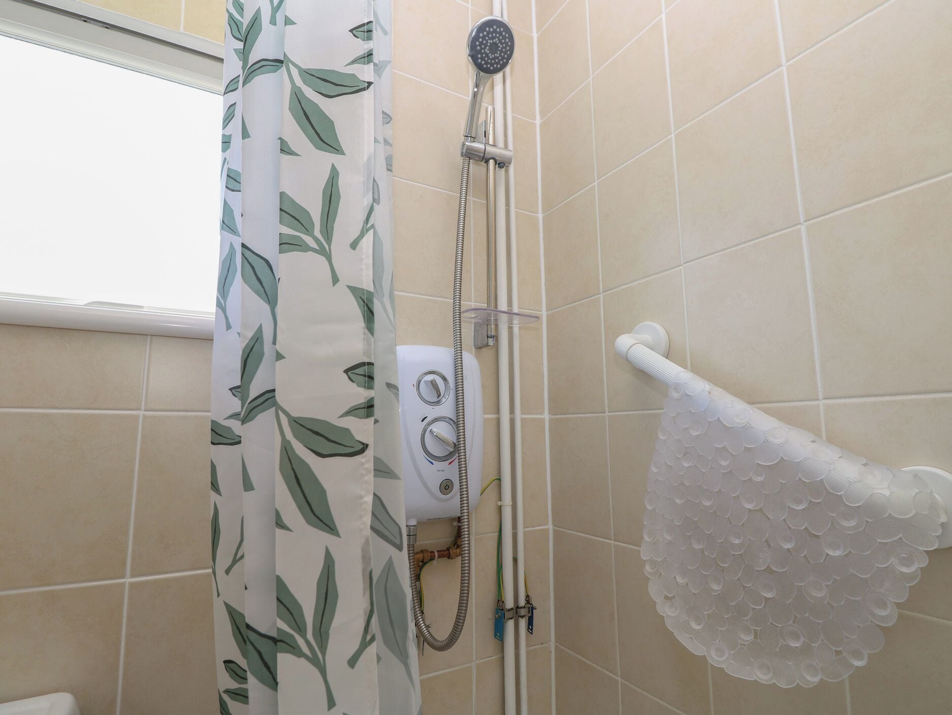 Um chuveiro com um chuveiro branco, um painel de controle e um porta-toalhas branco.
