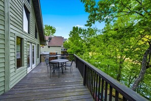 A wooden deck with a table and chairs, overlooking a lush green landscape. - Lakefront Cabin with Hot-tub and Dock in Tennessee (Speedwell)