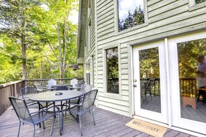 A deck with a round table and chairs, a welcome mat, and a sliding glass door. - Lakefront Cabin with Hot-tub and Dock in Tennessee (Speedwell)