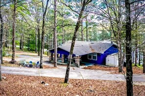 Eine blaue Holzhütte mit Veranda, umgeben von Bäumen.