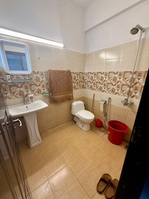 A bathroom with a toilet, sink, shower, and a red bucket. - 1BR Cozy Apartment, Diamond Mall and Residencia, Gulberg Greens (Islamabad)