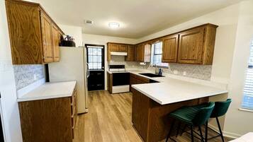 A modern kitchen with wooden cabinets, a central island with bar stools, and a built-in oven.
