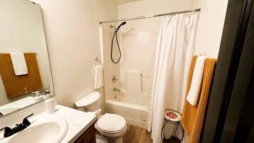 A bathroom with a bathtub, toilet, sink, and a mirror.