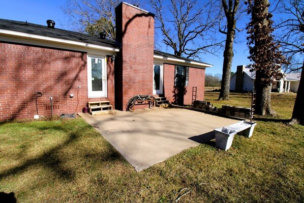 A brick house with a front porch, a chimney, and a concrete driveway.