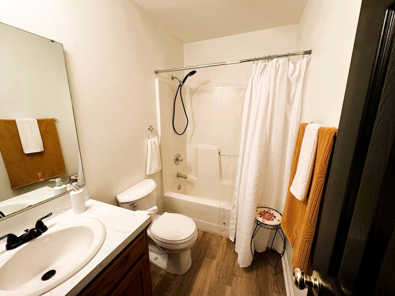 A bathroom with a bathtub, toilet, sink, and a mirror.