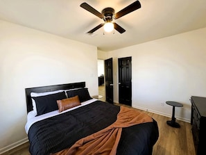Une chambre à coucher avec un lit, un ventilateur de plafond, une commode et une porte.