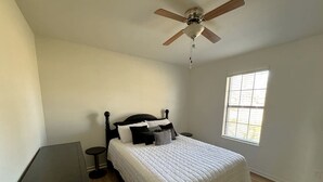 A bedroom with a bed, a ceiling fan, a window, and a small table. - Peaceful Retreat with Expansive Yards & Cozy Outdoor Spaces in Alexander, Arkansas (Alexander)