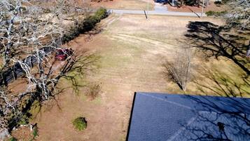 An aerial view of a residential area with a paved driveway, a lawn, and leafless trees.