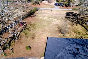 An aerial view of a residential area with a paved driveway, a lawn, and leafless trees.