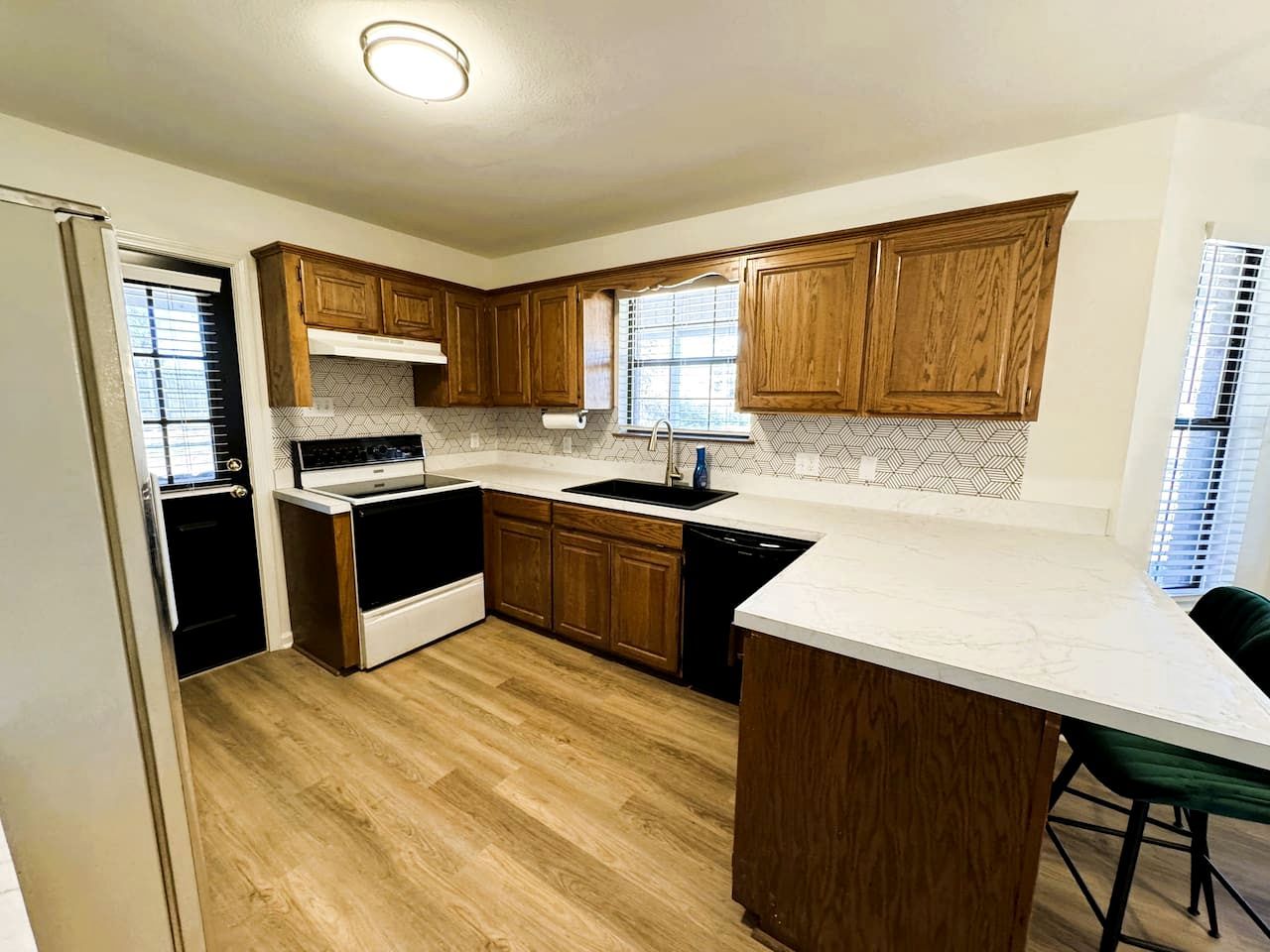 A kitchen with wooden cabinets, a white countertop, and a built-in oven.