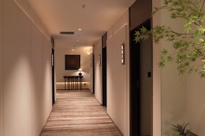Pasillo de hotel con piso alfombrado, un mostrador de recepción y un letrero en la pared.