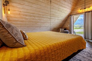 Ein Schlafzimmer mit Bett, einem Fenster mit Vorhängen und Blick ins Freie.