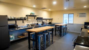 Una cocina con una mesa de madera, taburetes de bar azules, un microondas y un refrigerador.