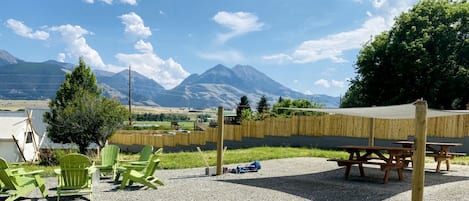 A patio area with green chairs, a picnic table, and a view of mountains.