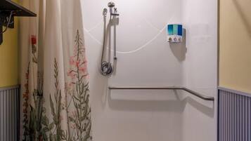 A shower with a floral curtain, a handrail, and a control panel.