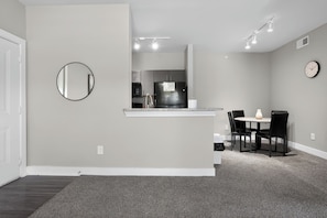 A modern kitchen with a refrigerator, microwave, and sink. There is a dining area with a table and chairs. - Bright & spacious 1bedroom retreat (New Braunfels)