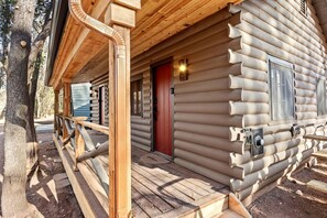 Une cabane en rondins avec une véranda en bois, une porte rouge et une plaque numérotée.