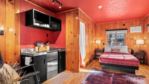 A compact room with a kitchenette, a bed, and a window. - Rustic-Chic Cabins with Scenic Woodland Views Near Garden of the Gods in Colorado Springs, Colorado (Colorado Springs)