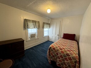 A bedroom with a bed, dresser, two windows with curtains, and a ceiling light. - Spacious Cottage for a Group Getaway with Views of Harvey Lake in Northwood, New Hampshire (Northwood)