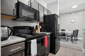 Eine moderne Küche mit Herd, Mikrowelle, Kühlschrank und Essbereich.