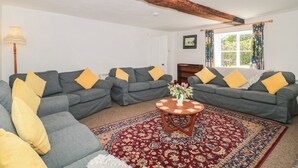 A living room with grey sofas, yellow cushions, a round wooden coffee table, and a patterned rug. - Walk Farmhouse (Gloucester)