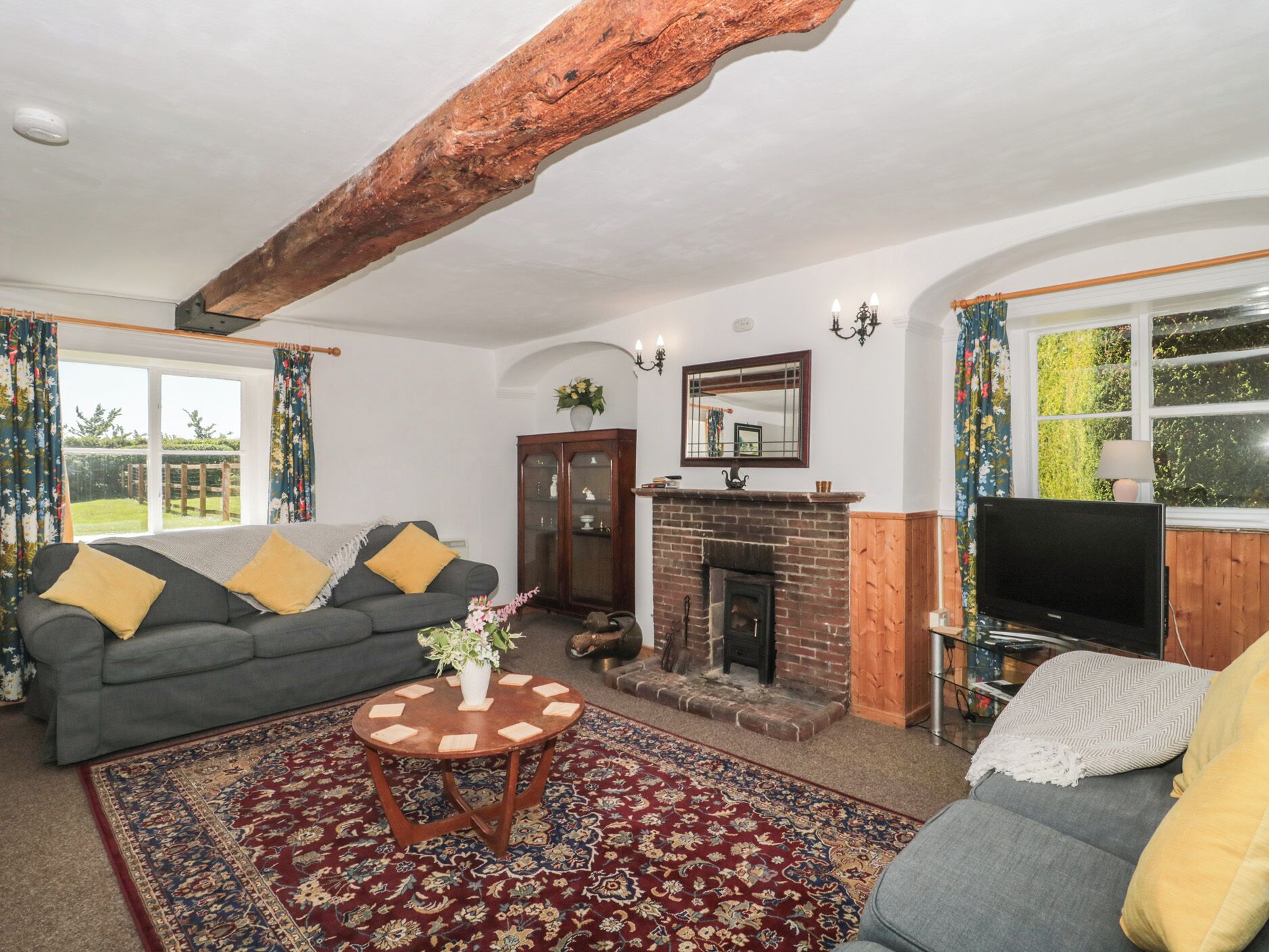A living room with a fireplace, a sofa, a television, and a round wooden table.