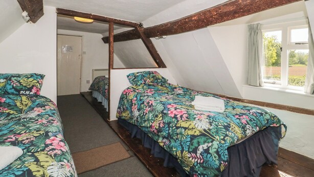A room with two beds, a window with curtains, a door, and a ceiling light. - Walk Farmhouse (Gloucester)