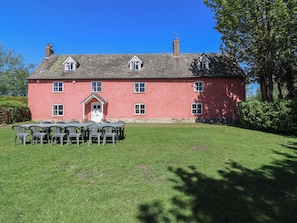 A red brick building with a white door and multiple windows, surrounded by a well-maintained lawn and outdoor seating area. - Walk Farmhouse (Gloucester)