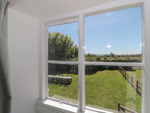 A room with a large window overlooking a grassy area with a table and chairs outside. - Walk Farmhouse (Gloucester)