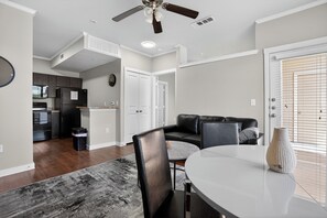 A modern kitchen with dark appliances, a dining area with a round table, and a living room with a black leather sofa. - Modern 1br living in New Braunfels (New Braunfels)