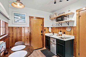Een kleine keuken met houten lambrisering, een magnetron en een spoelbak.