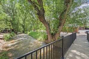 Ein Fluss fließt durch einen Park mit Bäumen und einem Metallzaun.